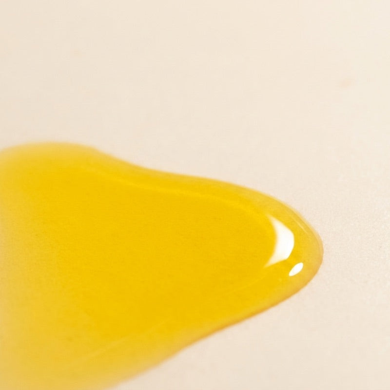 The golden texture of Timeless Elixir, swatched on a pale surface
